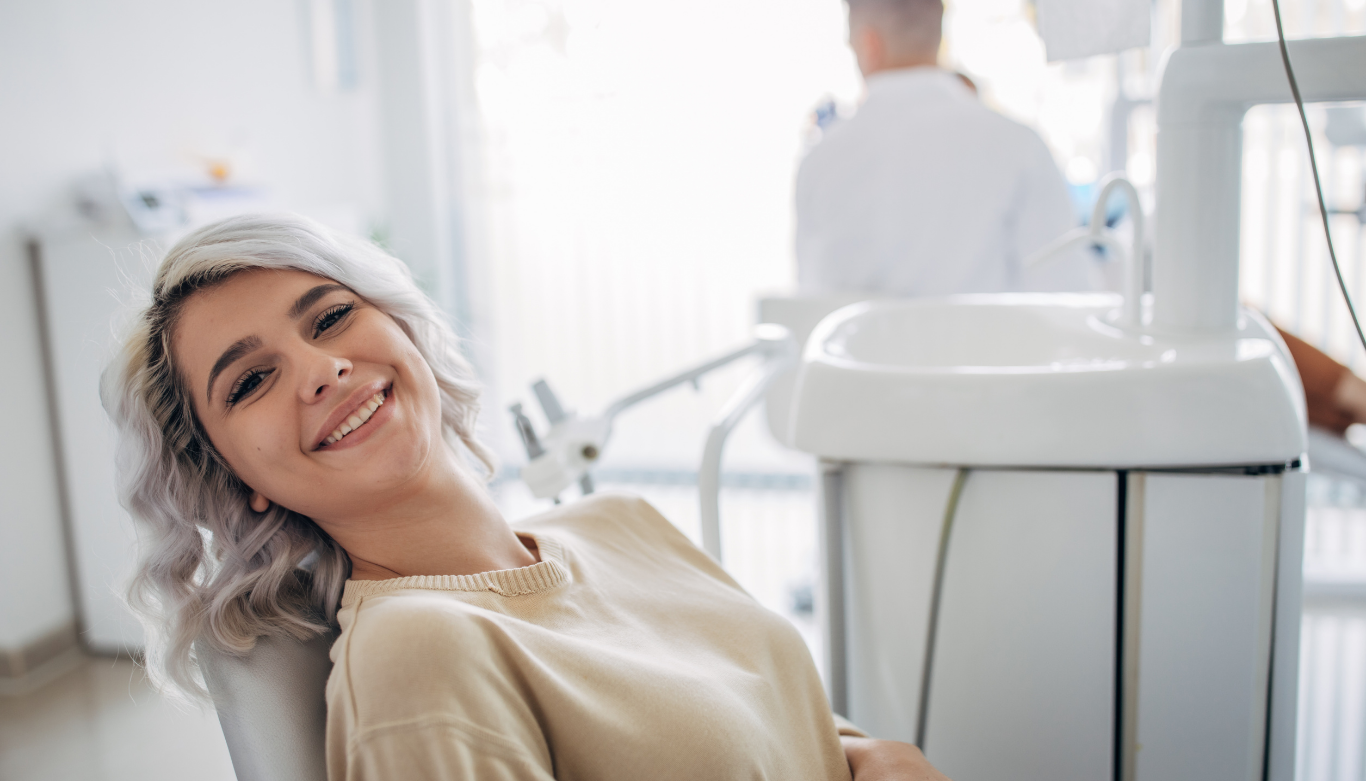 emu-plains-family-dental-wisdom-teeth-orthodontics Smiling woman sits in a dental chair in a modern clinic with dental equipment nearby.